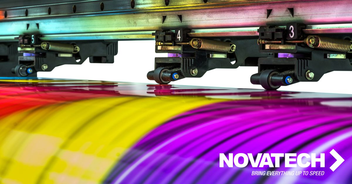 A large format printer's print heads are actively applying a vibrant, swirling pattern onto a substrate, with the