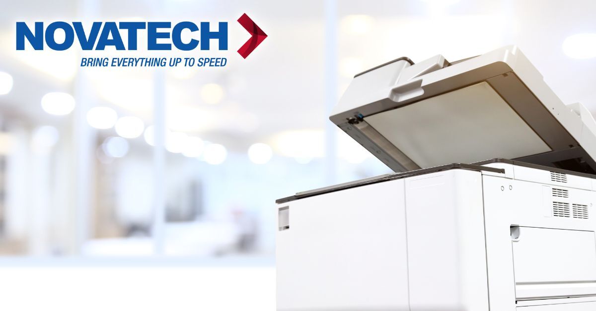 A white copier with its lid open is shown in the foreground, with the