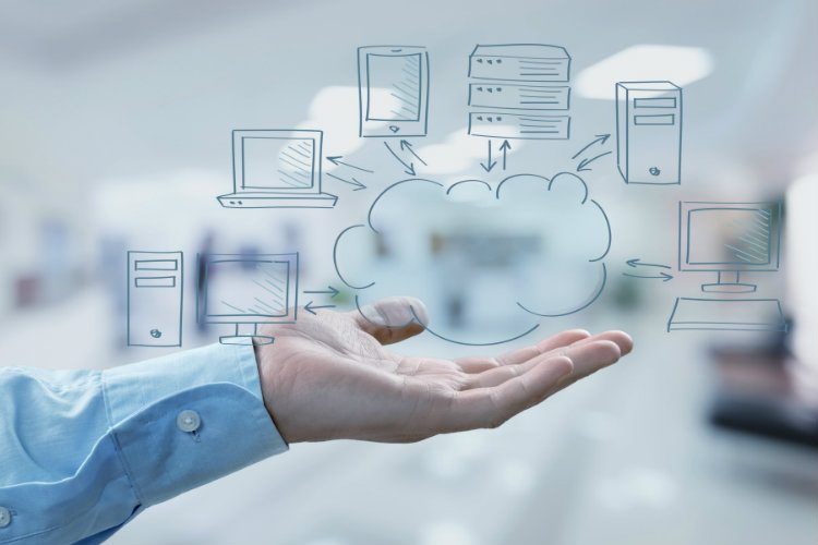 A hand holds a cloud diagram illustrating a network of computers and servers.