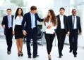 A diverse group of business professionals walks together in an office environment.