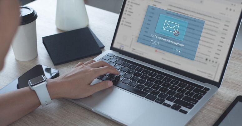 A person's hand is typing on a laptop keyboard, with a pop-up message on the screen asking if they want to 
