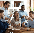 A group of colleagues is enjoying pizza and drinks together in a casual office setting.