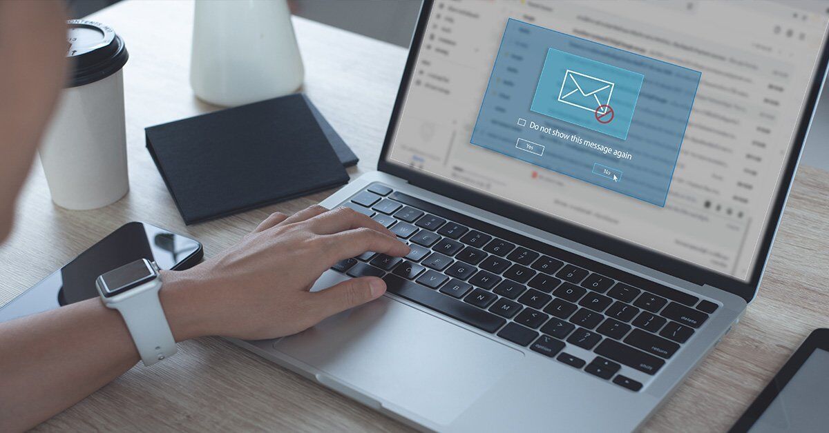 A person's hand is typing on a laptop keyboard, with a pop-up message on the screen asking if they want to 