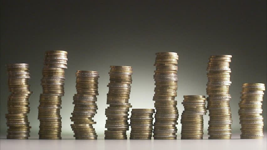 Stacks of coins are arranged in a bar graph-like pattern against a dark background.
