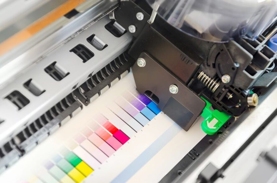 A color calibration chart is being printed and analyzed by a printer's internal mechanism.
