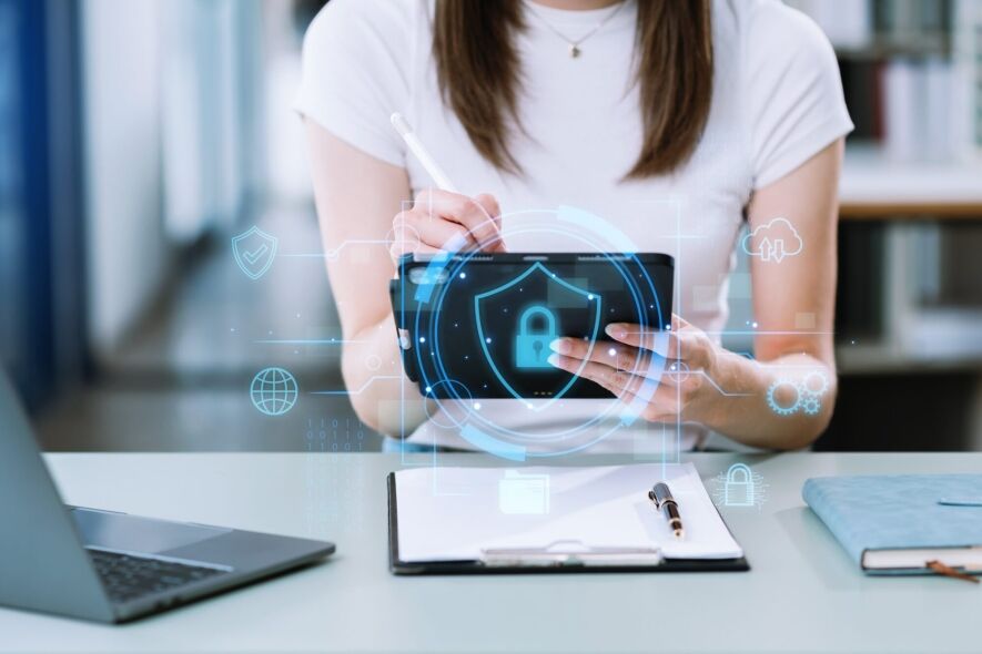 A person uses a tablet with a digital security interface, surrounded by icons representing data, networks, and cloud