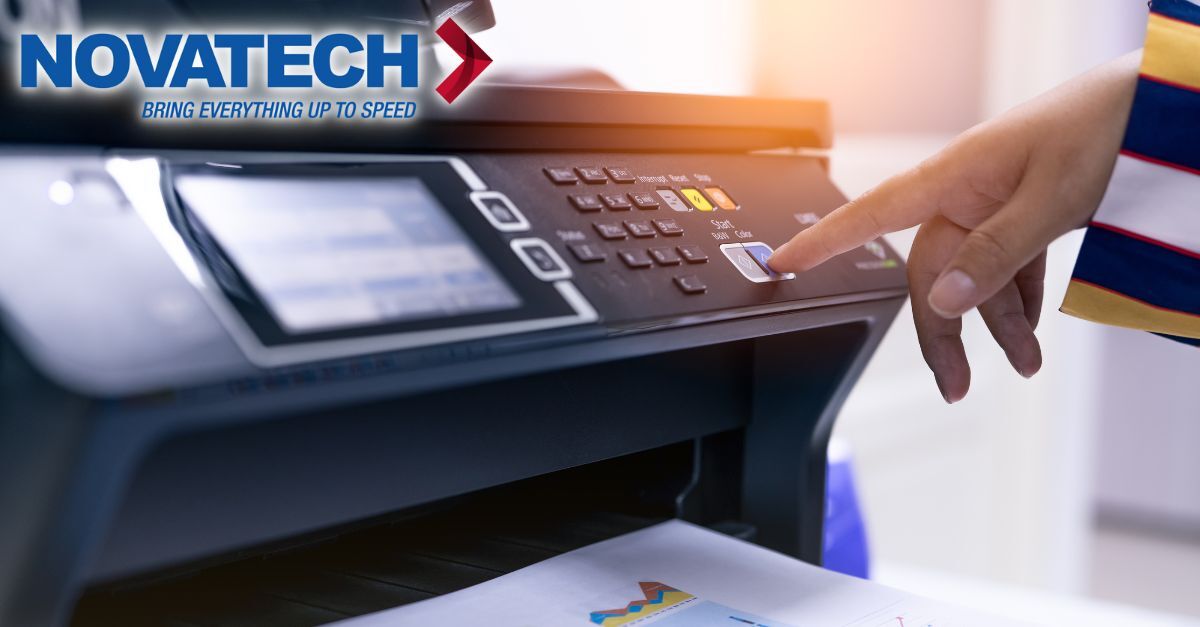 A hand presses a button on a printer with the Novatech logo visible.