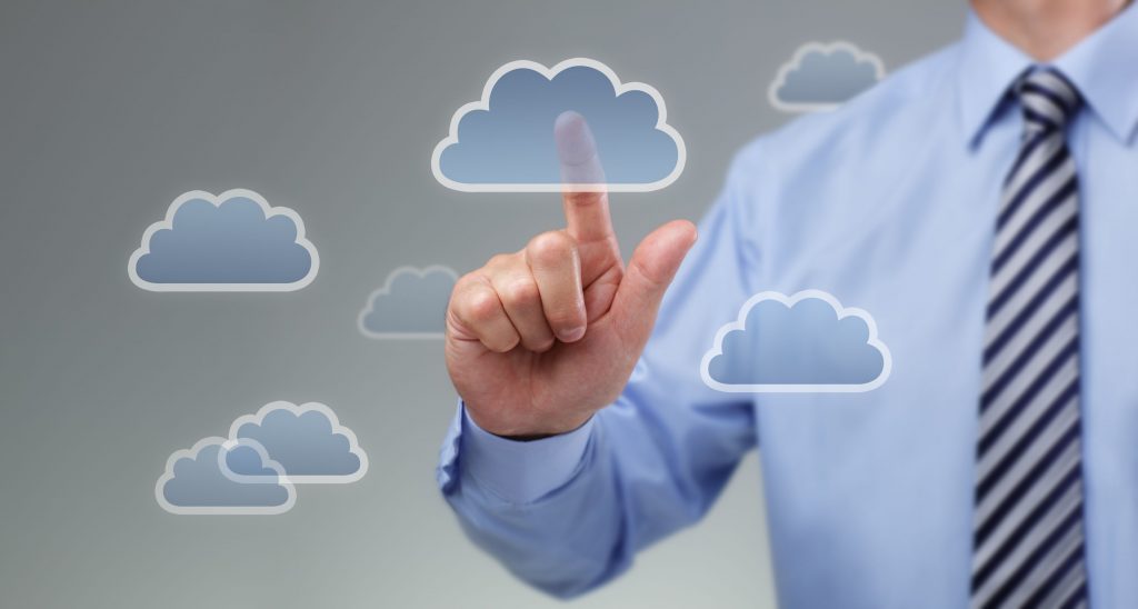 A man in a blue shirt and tie touches a cloud icon, symbolizing cloud computing.