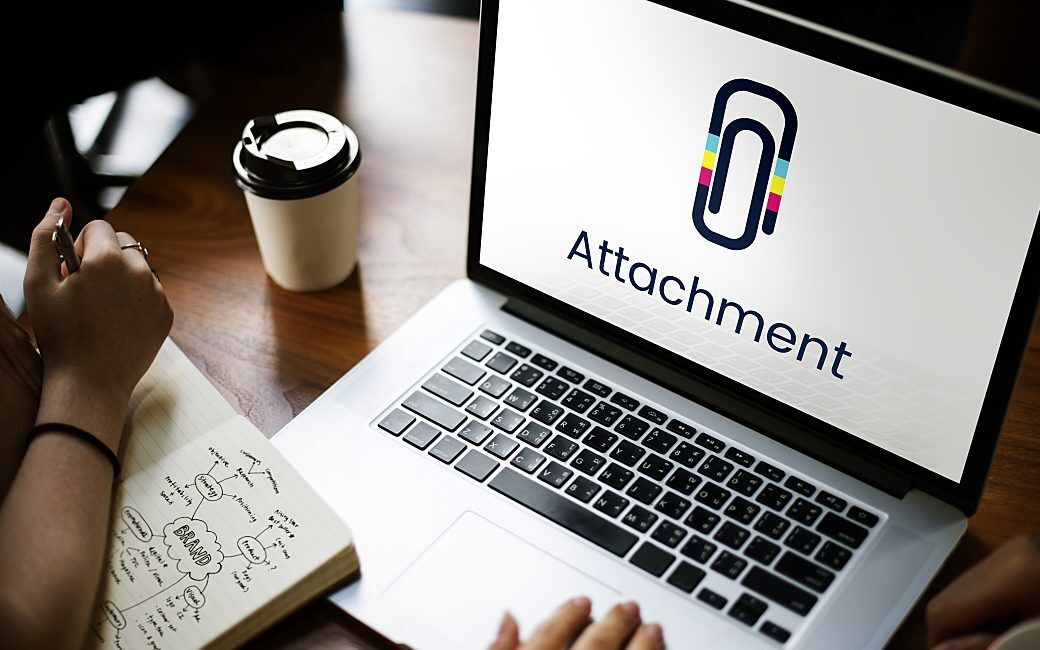 A person is working on a laptop displaying a paperclip icon and the word 