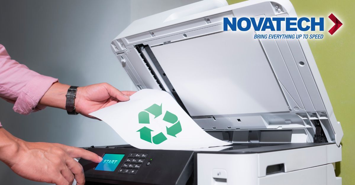 A person is placing a document with a recycling symbol into a printer, suggesting a focus on eco-friendly printing