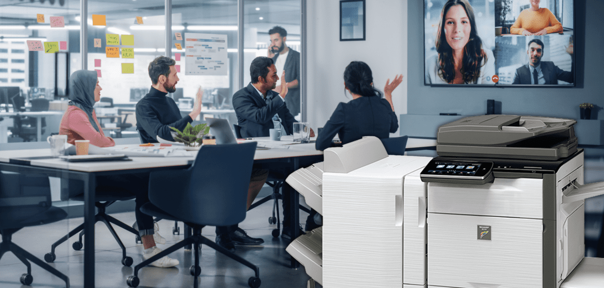 A diverse group of colleagues collaborates in a modern office, with a video conference displayed on a screen and a