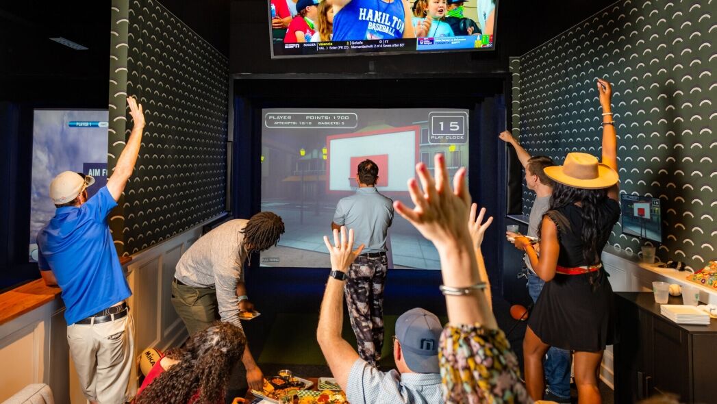 A group of friends enjoys a virtual basketball game in a modern entertainment venue.