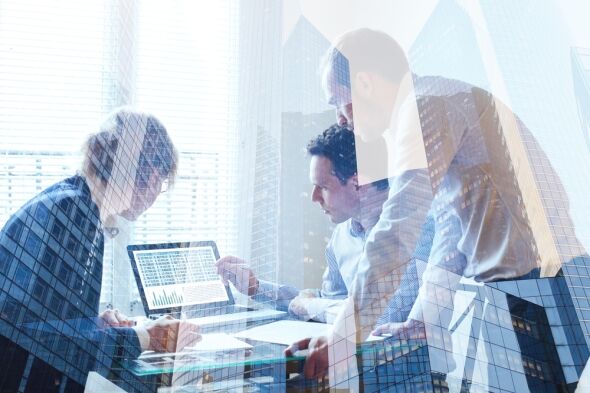 Three business professionals collaborate over a laptop displaying financial data and documents, superimposed with a