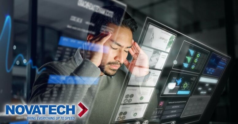 A stressed man with his hands on his temples is looking at a futuristic holographic display showing various charts and