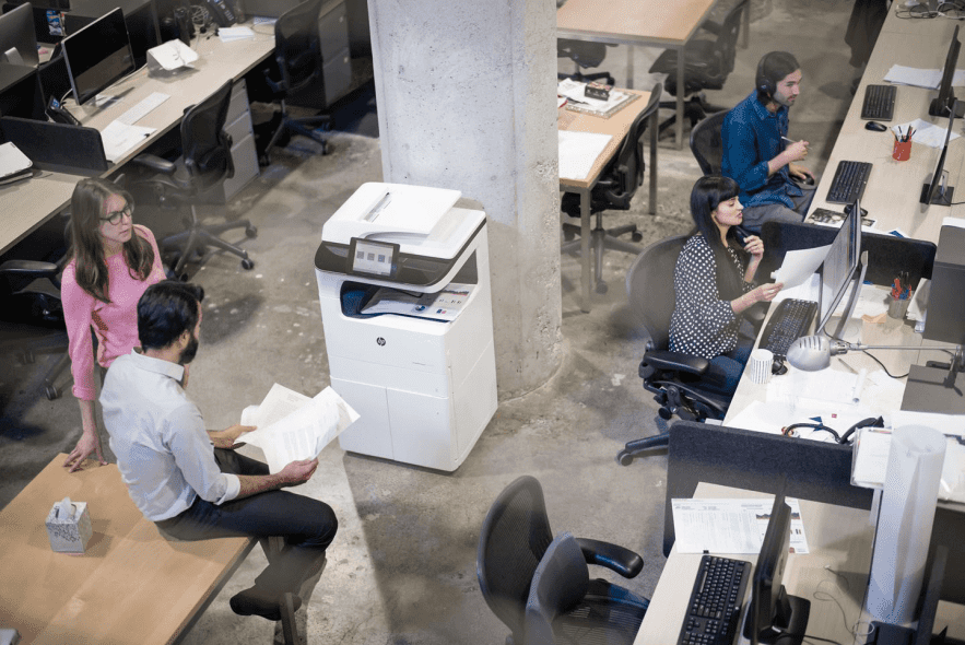 A diverse group of colleagues collaborate and work at their desks in a modern office environment.