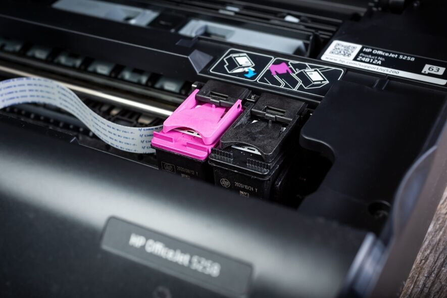 A close-up shot shows the inside of an HP OfficeJet 5258 printer, focusing on the magenta and black ink cartridges and