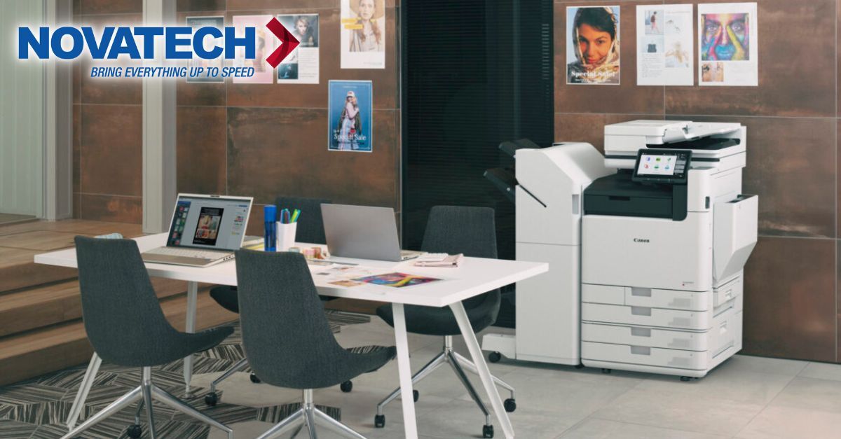 A modern office space features a Canon copier and a conference table with laptops and chairs.
