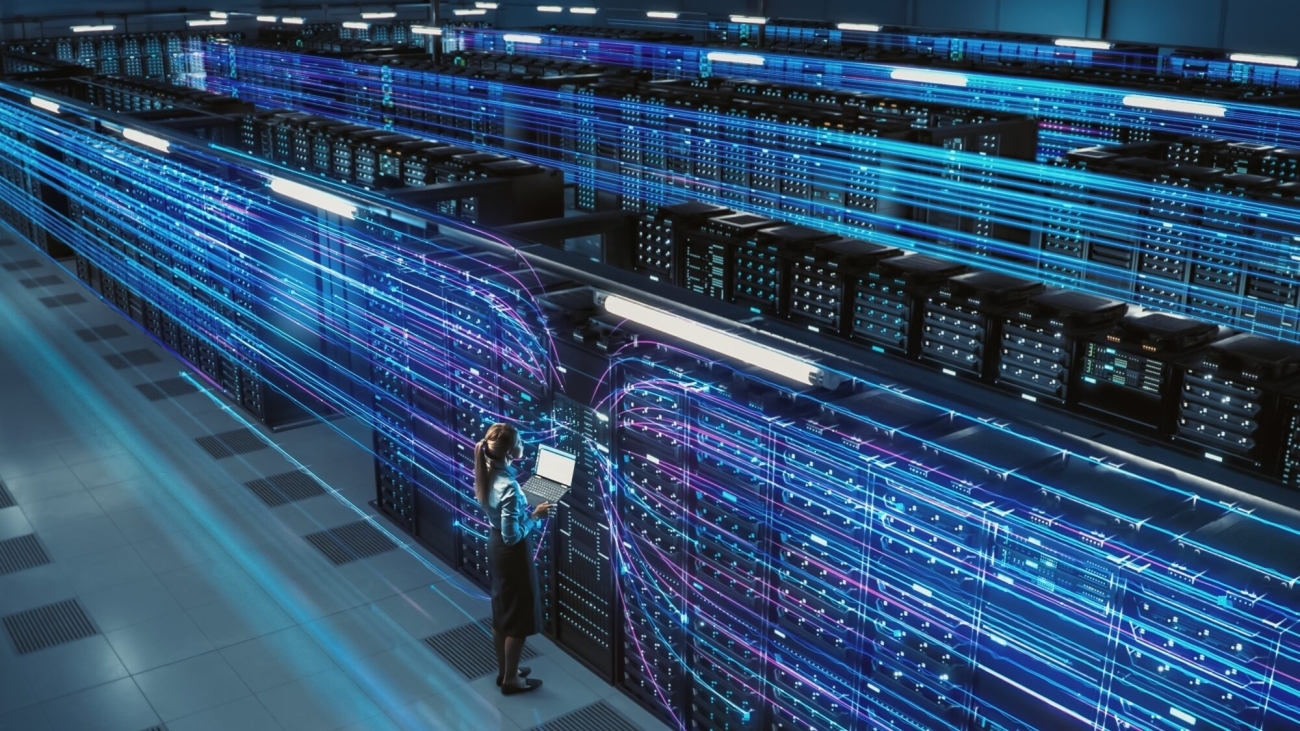 A woman monitors and manages servers in a vast data center, surrounded by glowing blue and pink lines representing