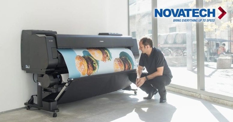 A man observes a large Canon printer producing a vibrant print of hamburgers, situated in a bright room with a Novatech