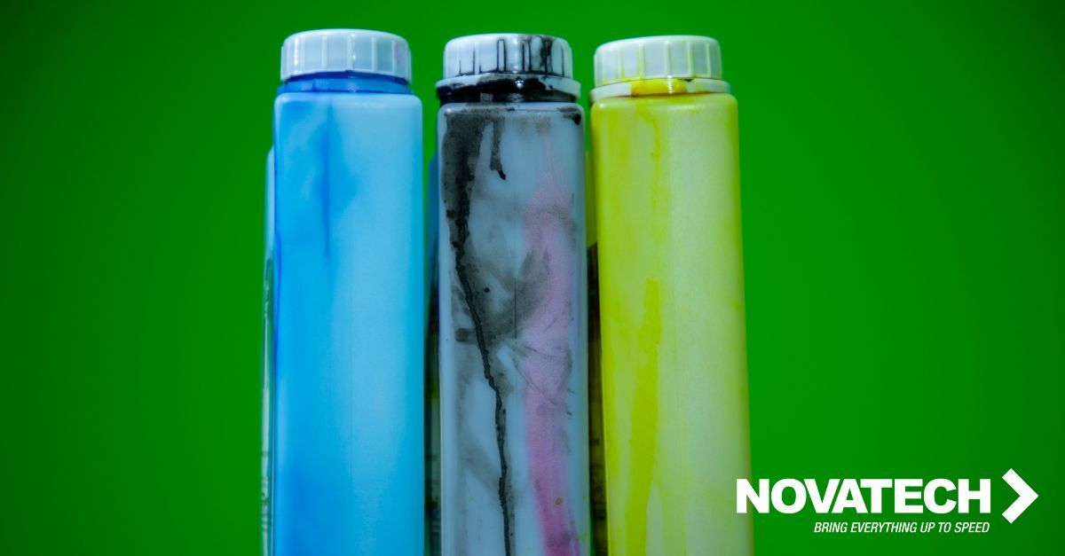 Three bottles of ink, one blue, one black and pink, and one yellow, are displayed against a bright green background